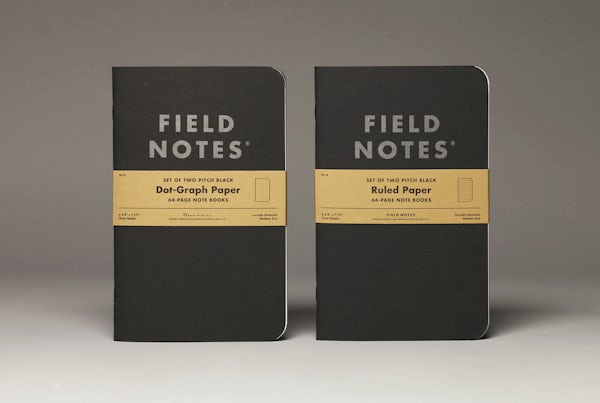 Two Pitch Black Notebooks standing on end, one in dot-graph paper style and the other in ruled paper style.