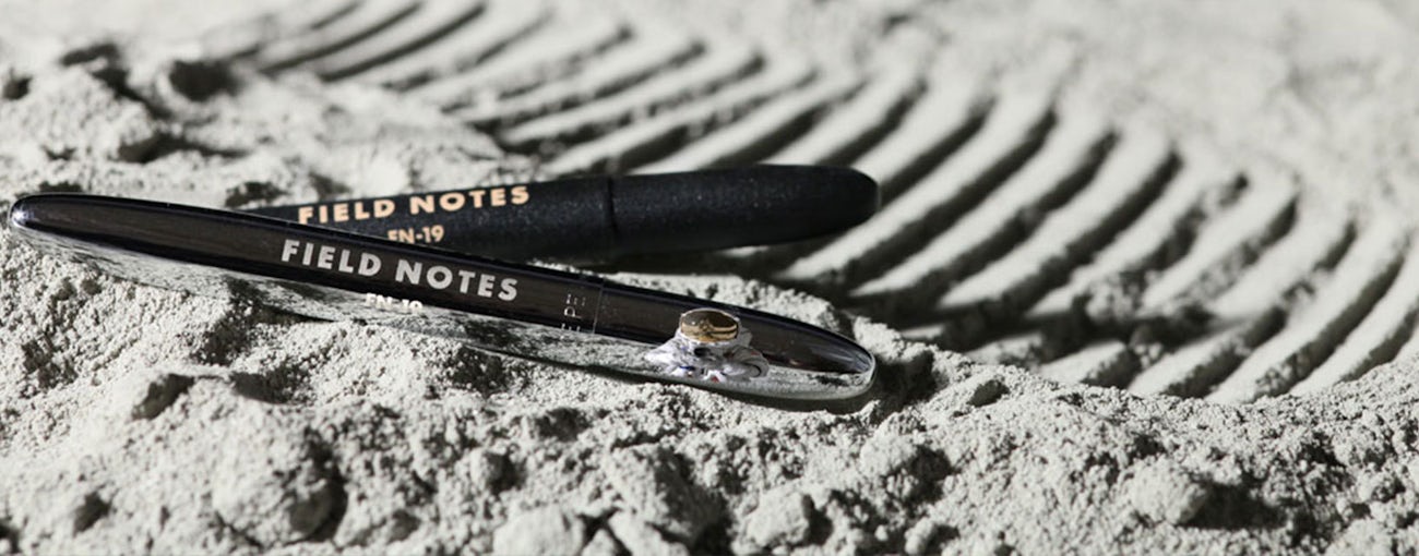 Black and chrome color space pens shown laying on the surface of the moon.